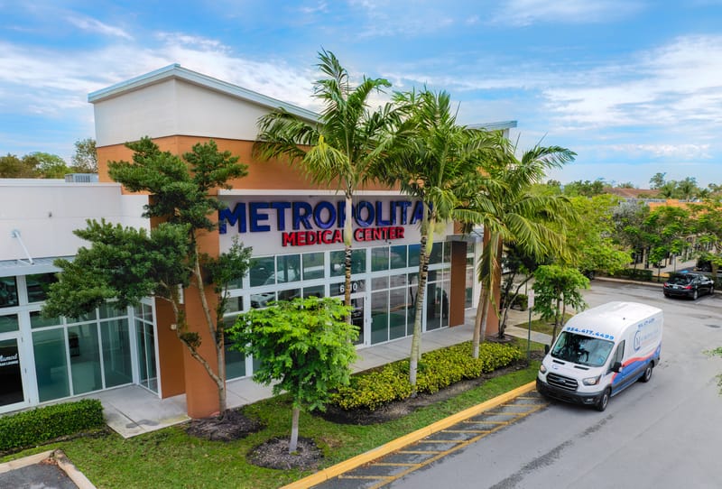 Aerial view of the Metropolitan Medical Center building at 6510 N University Dr, with palm trees and a transport van