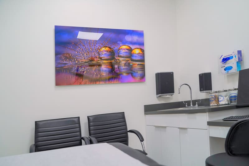 Exam room with two chairs, a sink and wall art